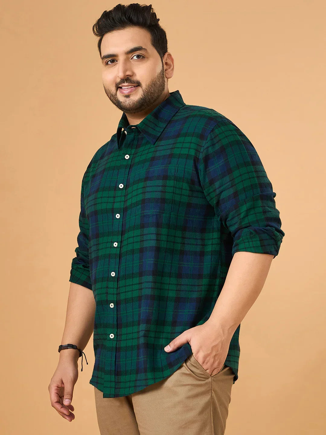 Plus size man in green and blue checkered shirt and khaki pants on beige background