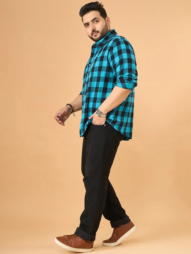 Plus size man modeling blue checkered shirt with black jeans and brown sneakers