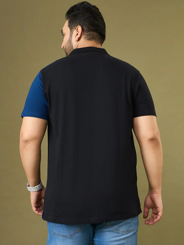 Back view of a man wearing a plus size black and blue polo t-shirt with jeans