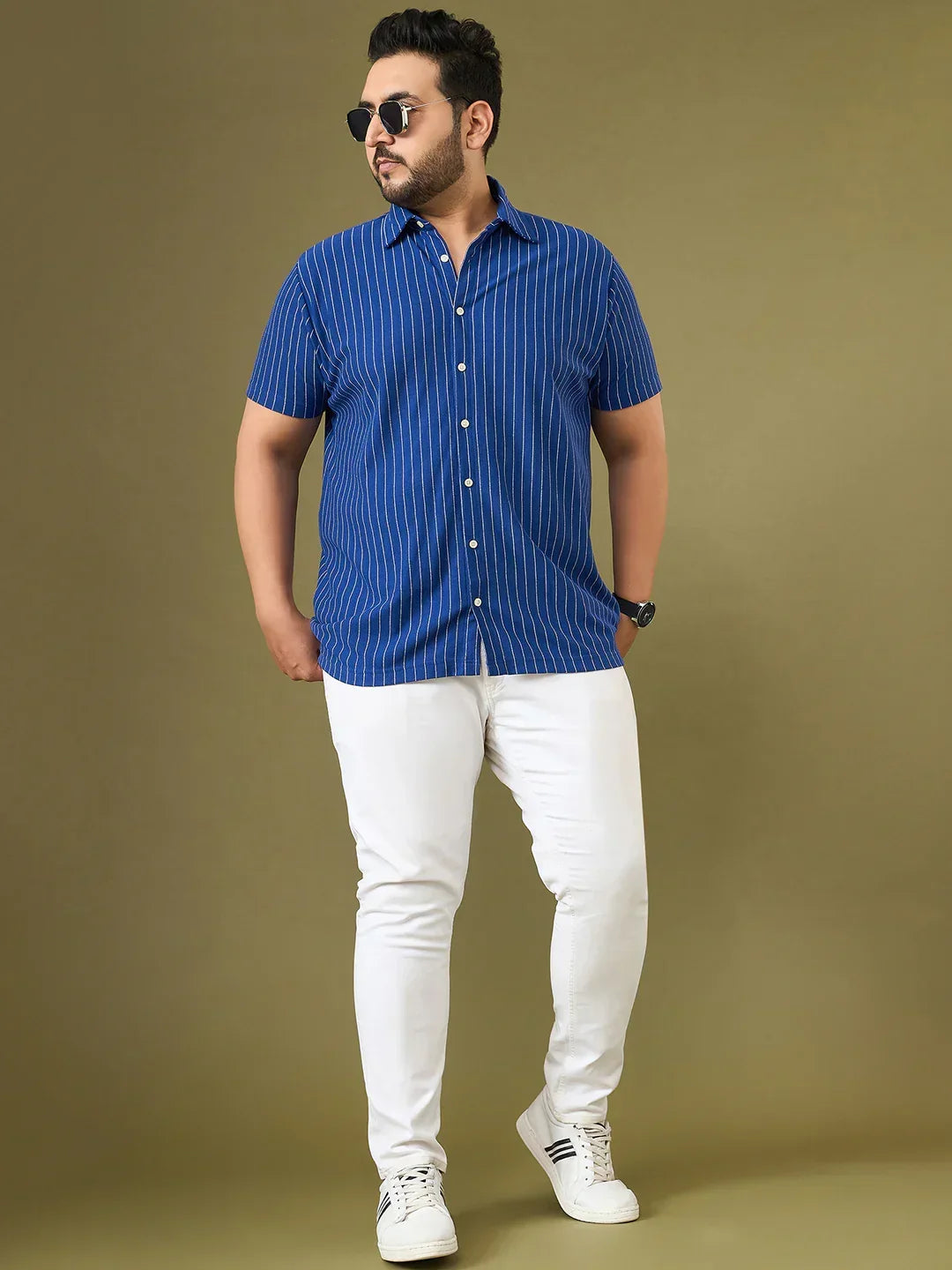 Plus size man wearing a blue pinstripe short sleeve shirt with white jeans and sneakers