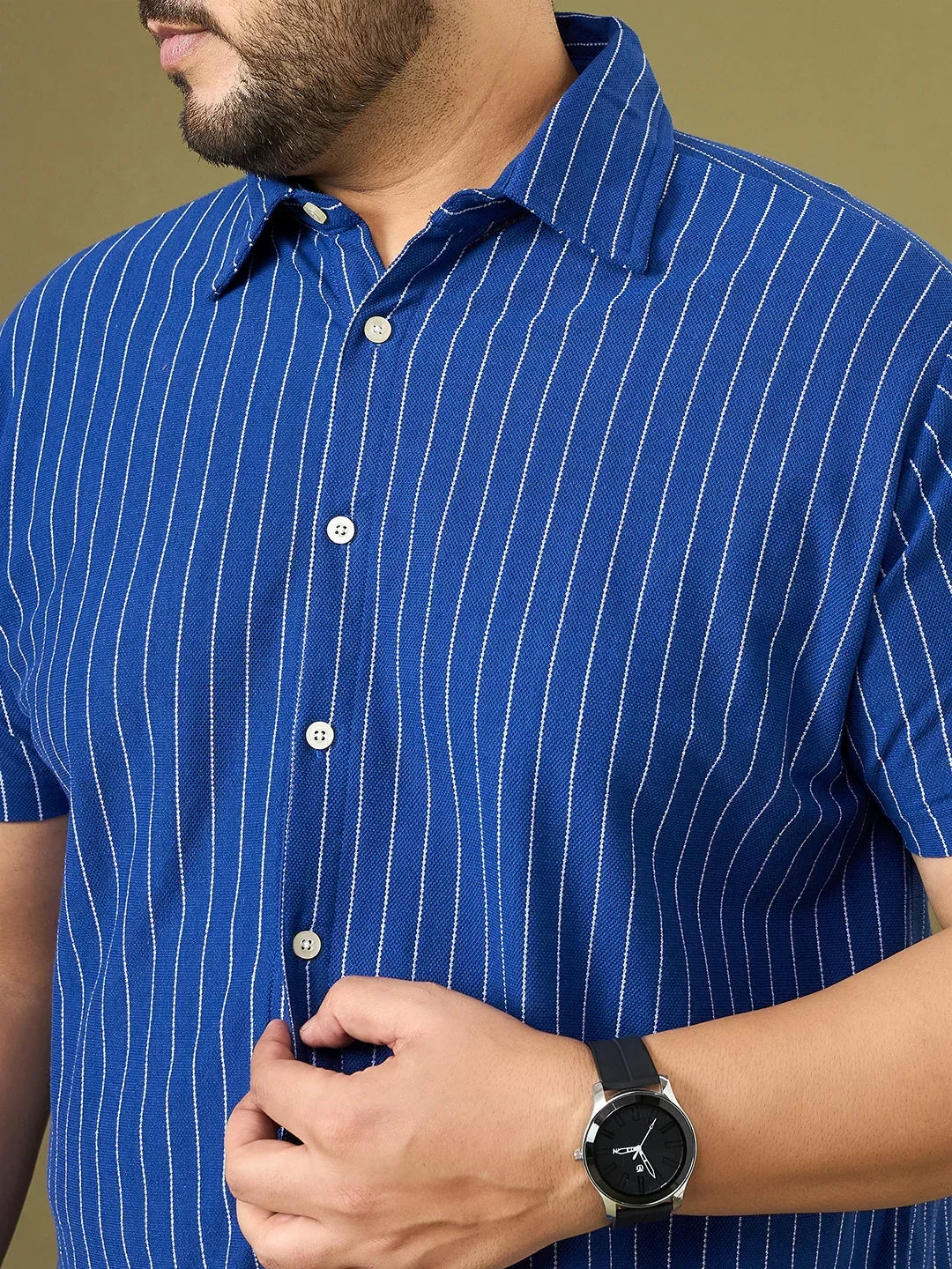 Close-up of man in blue vertical striped short sleeve shirt, wearing black wristwatch
