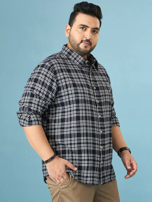 Plus size man wearing navy blue and white plaid shirt with rolled sleeves and beige pants