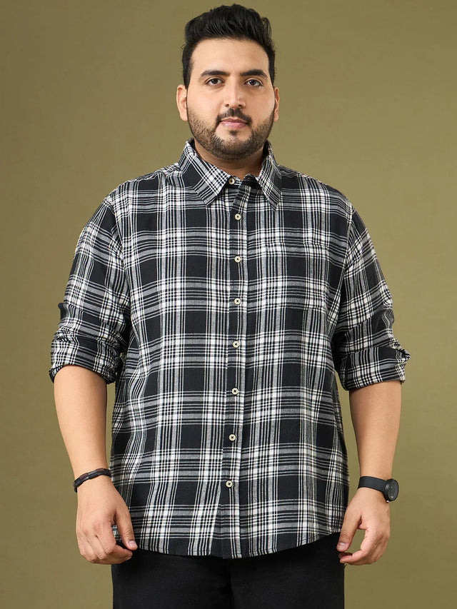 Plus size man in black and white checkered button-up shirt, standing against plain background