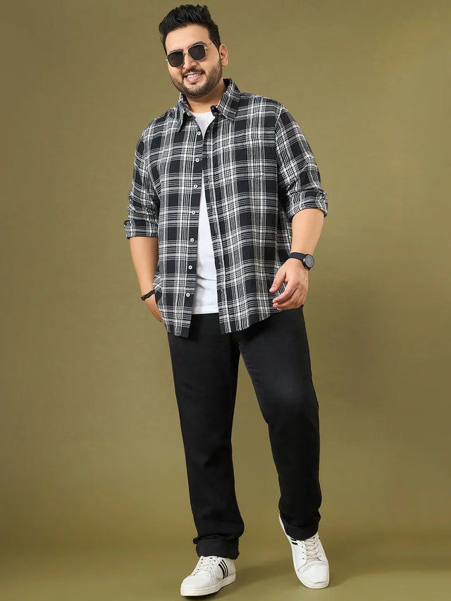 Plus size man in black and white plaid shirt, white t-shirt, black jeans, and sneakers