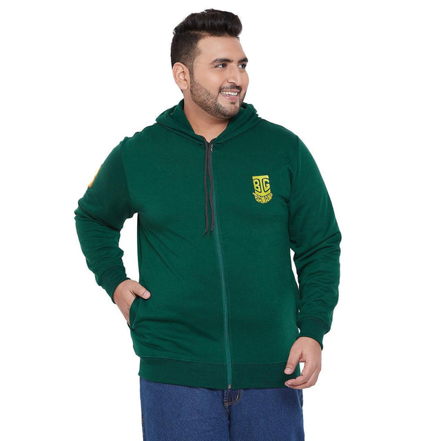 Plus size man in green zip-up hoodie with yellow chest logo and blue jeans