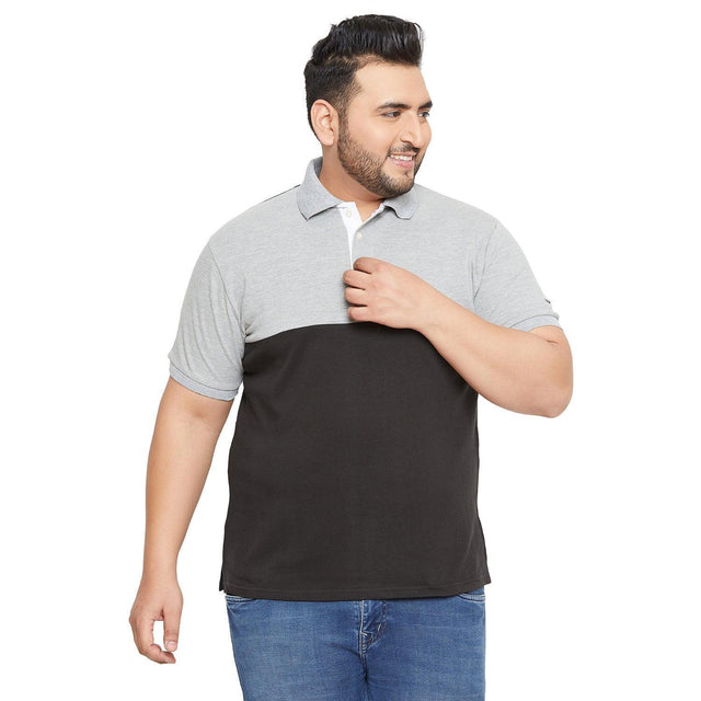Plus size man wearing a grey and black polo shirt and blue jeans on white background