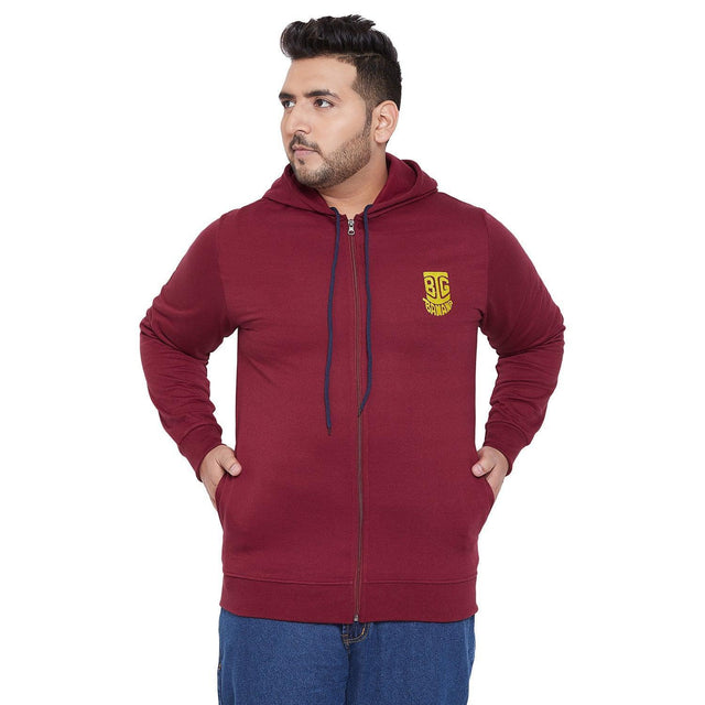 Plus size man wearing maroon zip-up hoodie with hood and yellow chest logo, casual style
