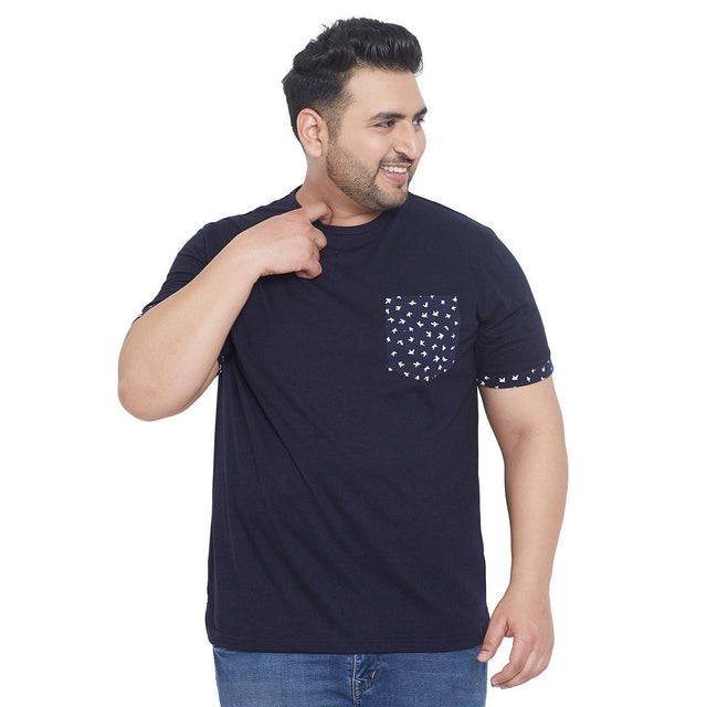 Plus size man wearing navy blue t-shirt with printed pocket and sleeve trim, blue jeans