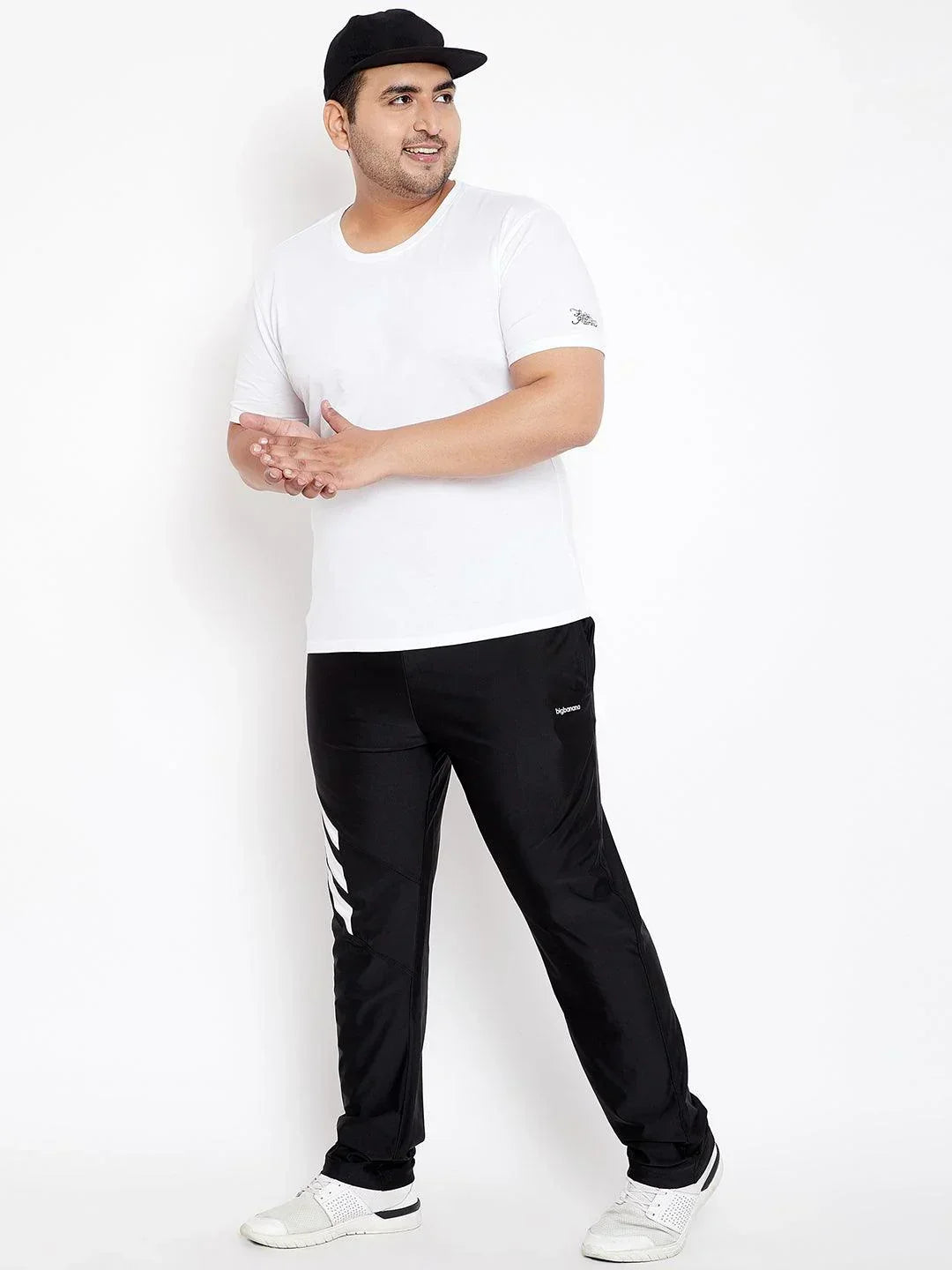 Plus size man wearing white t-shirt, black joggers with white stripes and cap, posing casually.