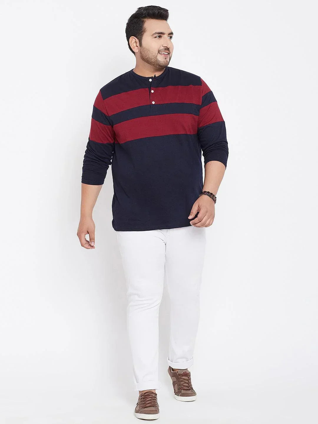 Plus size man in navy and maroon striped henley shirt with white jeans and brown sneakers
