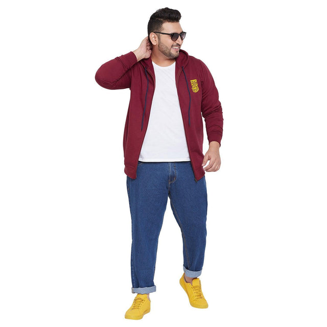Plus size man in maroon hoodie, white t-shirt, blue jeans, and yellow sneakers on white background