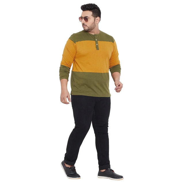Plus size man modeling a mustard and olive green colorblock henley t-shirt with black jeans