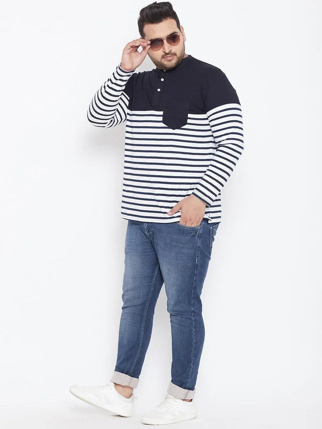 Plus size man wearing navy and white striped Henley shirt, blue jeans, and white sneakers
