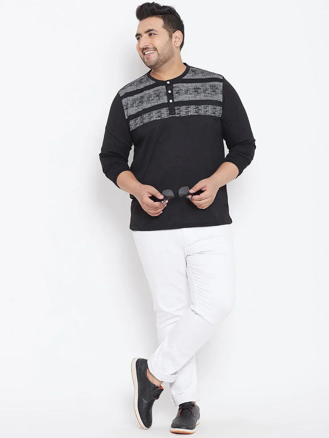 Plus size man wearing black long sleeve henley t-shirt with grey pattern and white pants