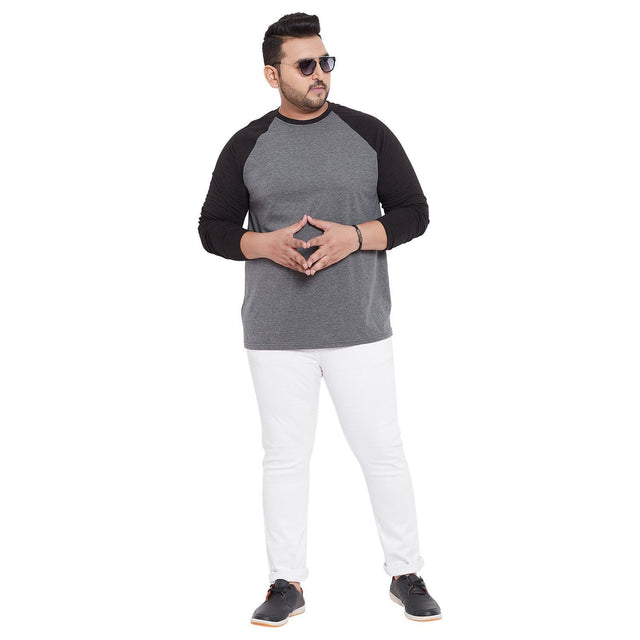 Plus size man in a grey and black raglan long sleeve t-shirt and white jeans