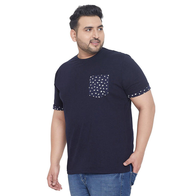 Plus size man wearing navy blue t-shirt with printed pocket and sleeve accents, paired with jeans