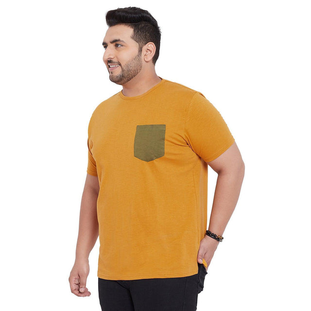 Plus size man wearing mustard yellow t-shirt with olive pocket and black jeans