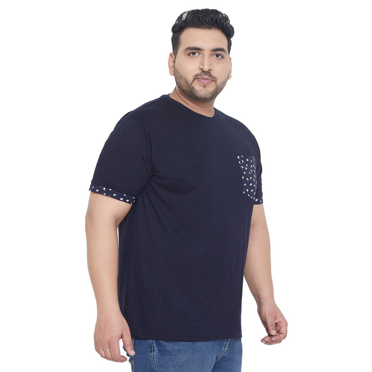 Plus size man in navy blue t-shirt with printed pocket and sleeve trim, paired with jeans