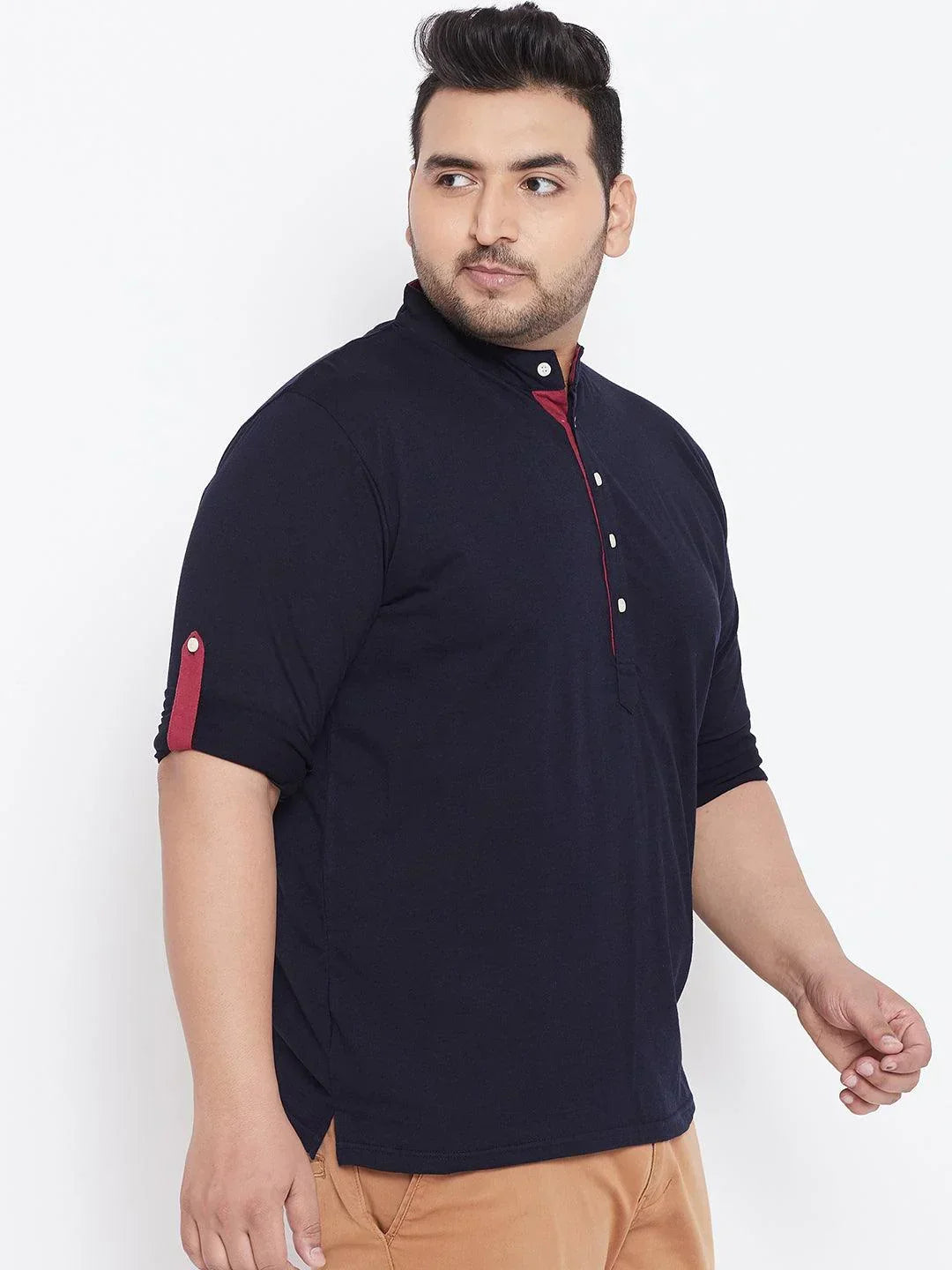 Plus size man wearing navy blue mandarin collar shirt with red button details and tan pants