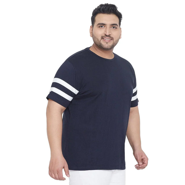 Plus size man wearing navy t-shirt with white sleeve stripes and white pants
