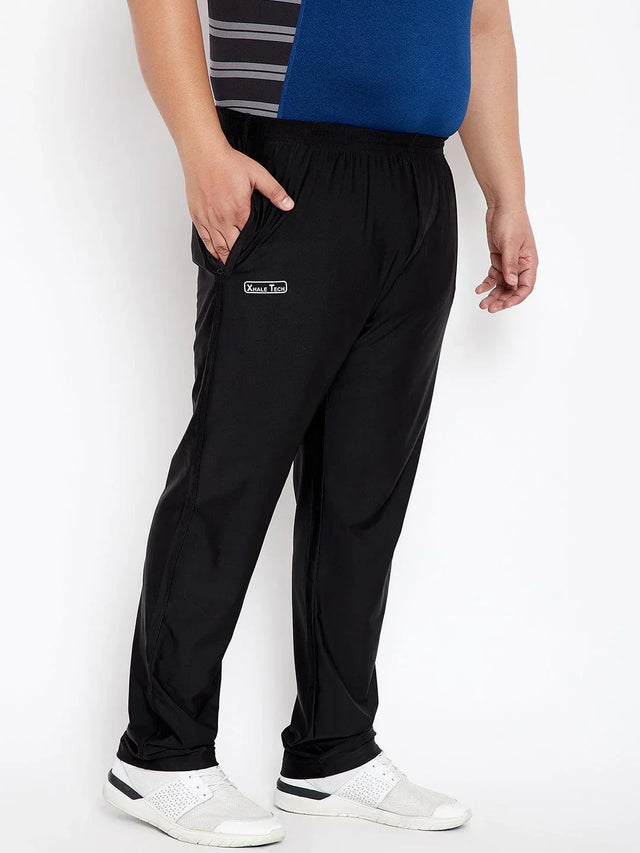 Plus size man in black athletic joggers with Xhale Tech logo, casual sneakers, hand in pocket