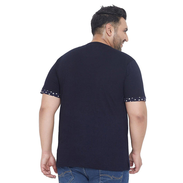 Back view of plus size man wearing navy blue t-shirt with printed sleeve detail and jeans