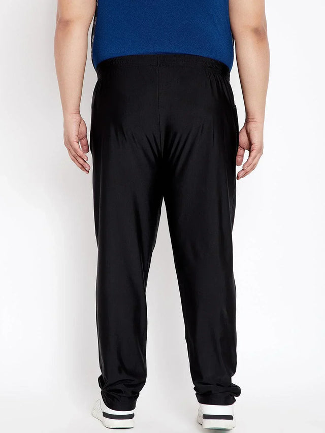Back view of man wearing black plus size joggers and white sneakers against white background
