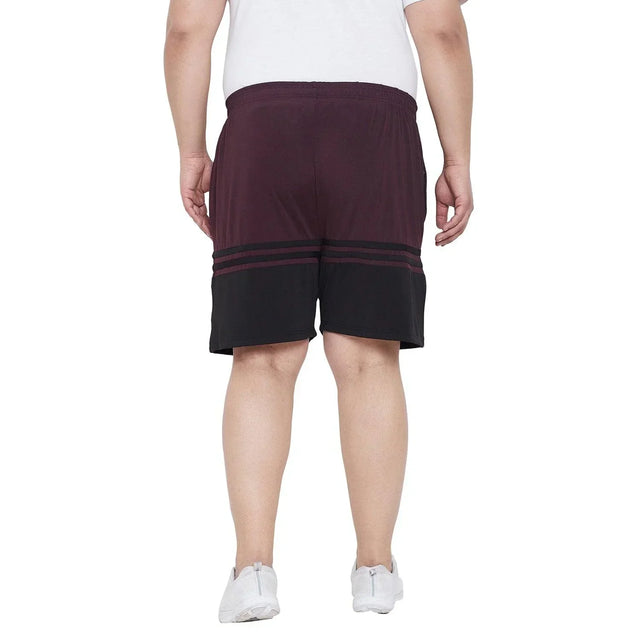 Back view of man in plus size maroon and black colorblock shorts, white sneakers