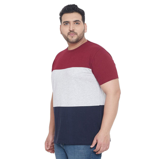 Plus size man wearing colorblock t-shirt in maroon, grey, and navy with blue jeans