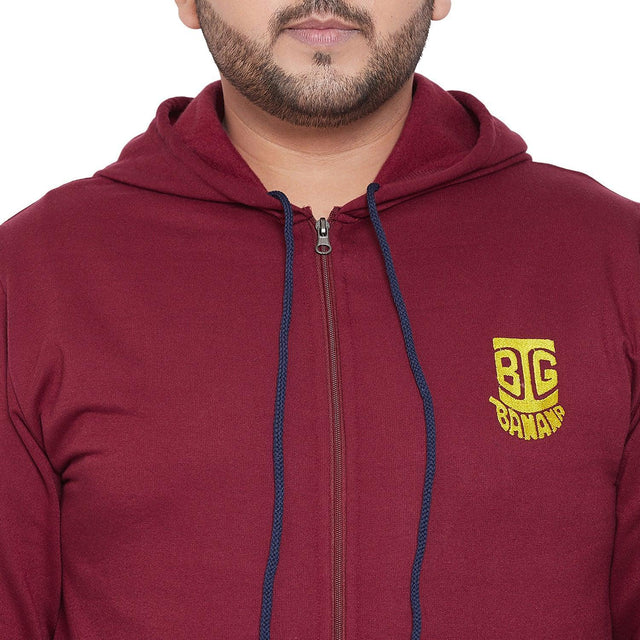 Close-up of a man wearing a maroon plus size zip-up hoodie with drawstrings and yellow chest logo