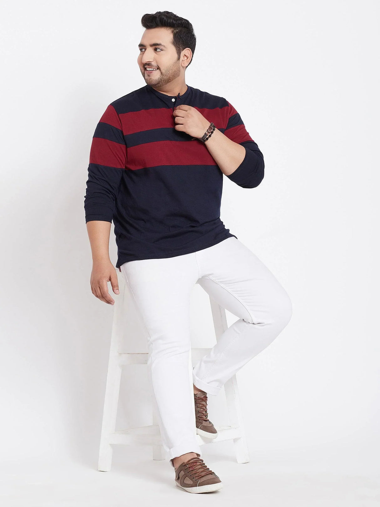 Plus size man in navy and maroon striped long sleeve t-shirt, white jeans, brown sneakers