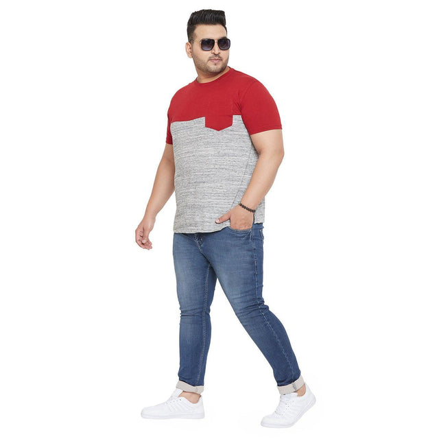 Plus size man in red and grey colorblock t-shirt, blue jeans, and white sneakers