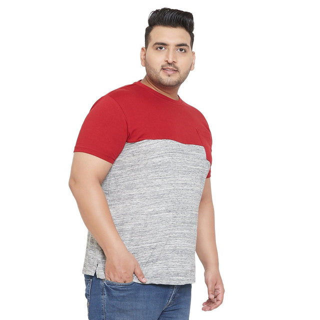 Plus size man wearing a red and grey colorblock t-shirt and blue jeans on white background