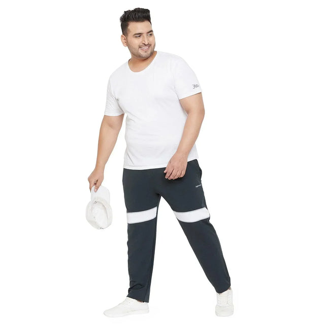 Plus size man in white t-shirt and black joggers with white stripes, holding a cap
