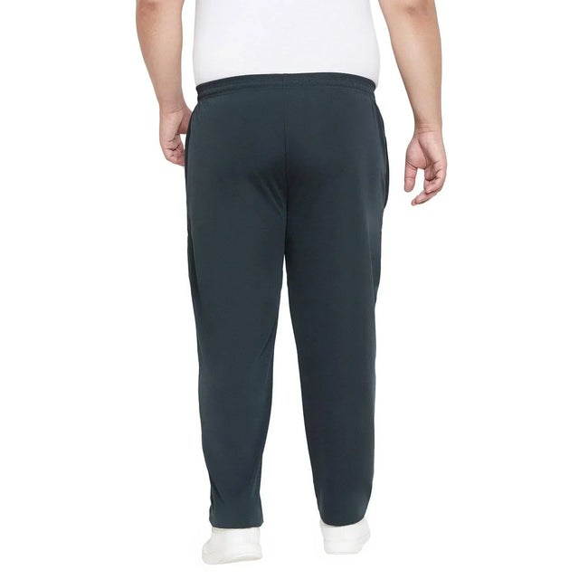 Back view of man wearing dark plus size joggers and white sneakers on white background