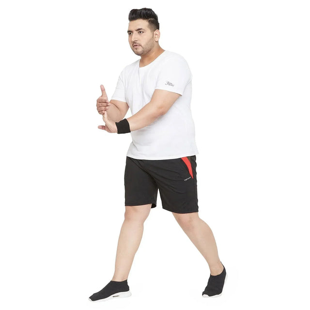 Plus size man in white t-shirt and black athletic shorts posing on white background