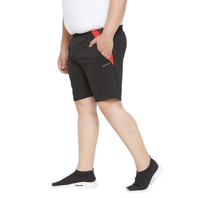 Plus size man wearing black athletic shorts with red accents and black slip-on sneakers