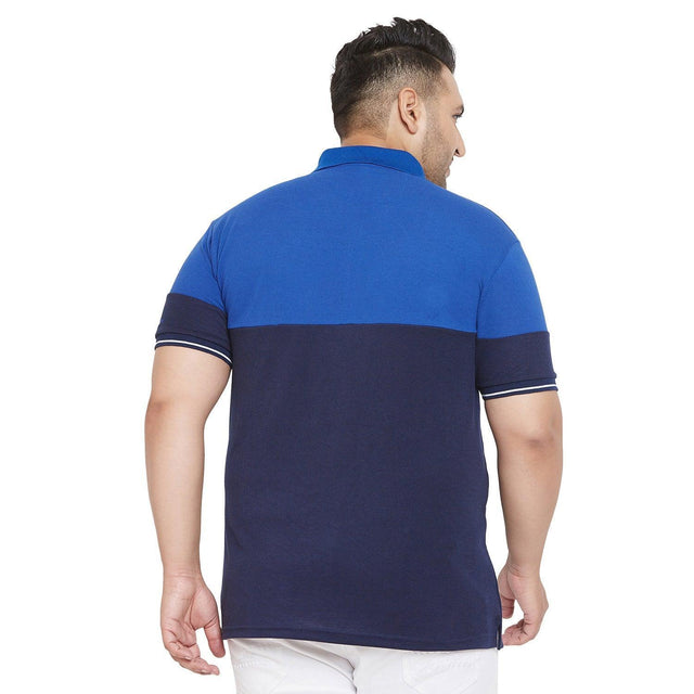 Back view of man in blue colorblock plus size polo t-shirt and white pants