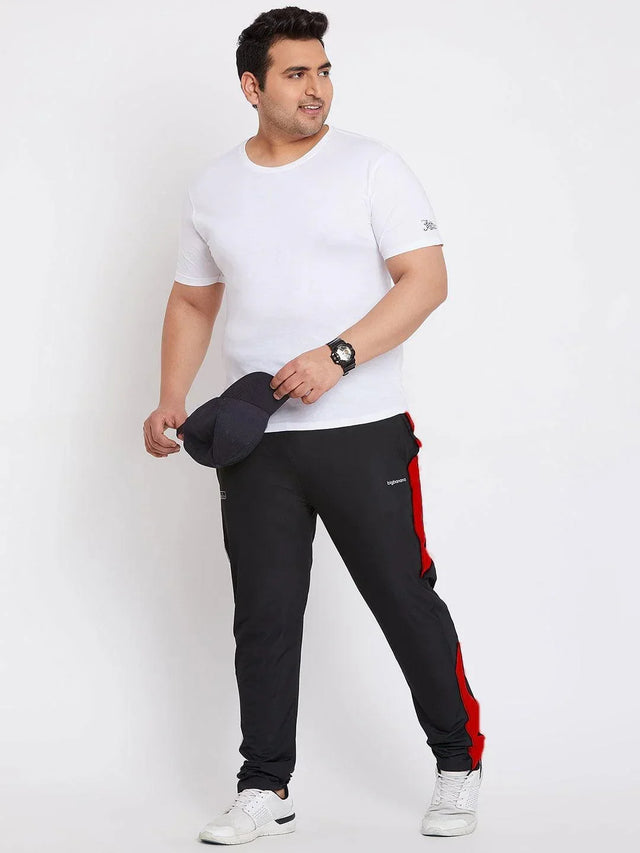 Plus size man in white t-shirt and black joggers with red side stripes, holding a cap