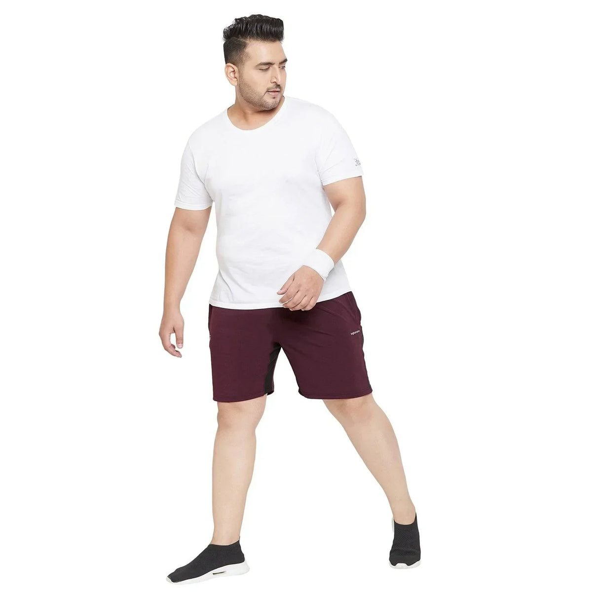 Plus size man in white t-shirt and maroon shorts posing against white background
