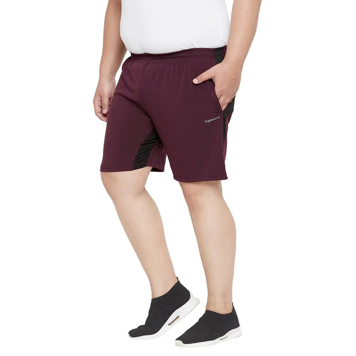 Plus size man wearing maroon athletic shorts with black panels, white t-shirt, and slip-on sneakers
