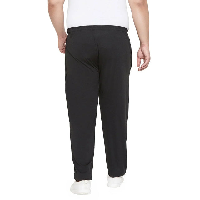 Back view of a man wearing black plus size track pants and white sneakers