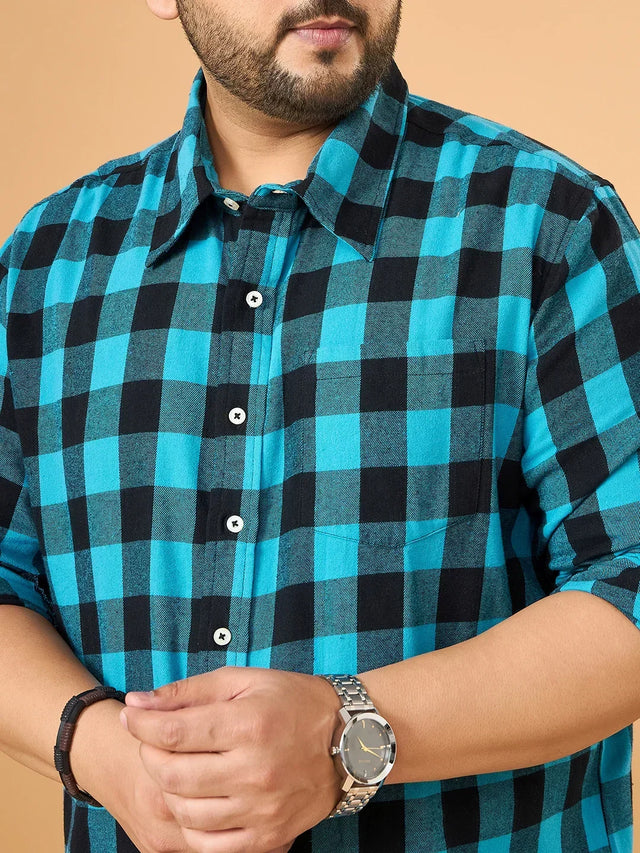 Man wearing blue and black checked plus size shirt with rolled sleeves