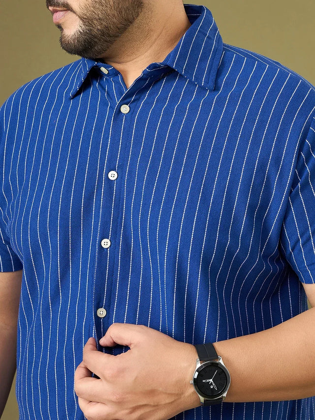 Close-up of man in blue vertical striped short sleeve shirt, wearing black wristwatch