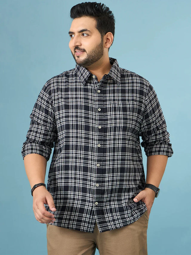 Plus size man in a black and white plaid shirt with rolled sleeves and khaki pants