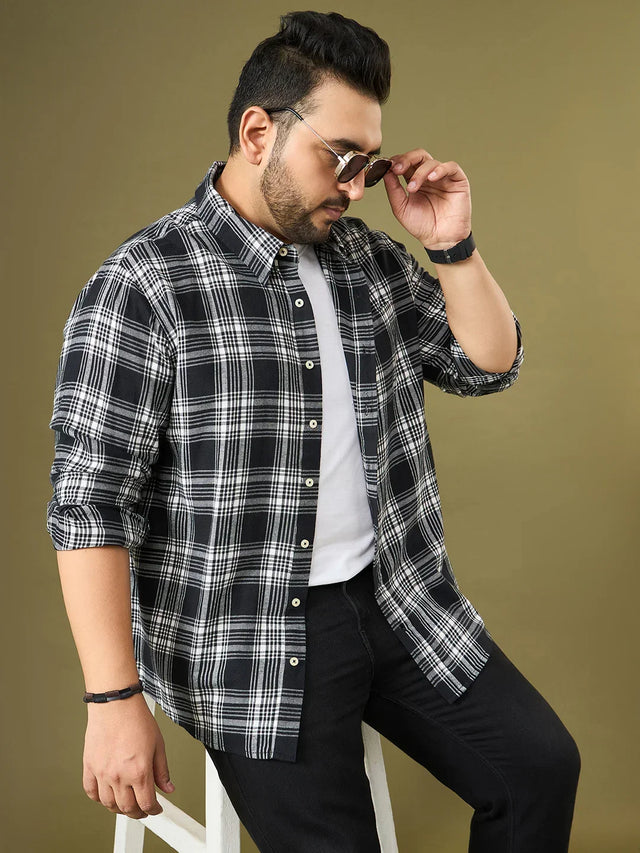 Plus size man in black and white checkered shirt, white tee, black jeans, sunglasses