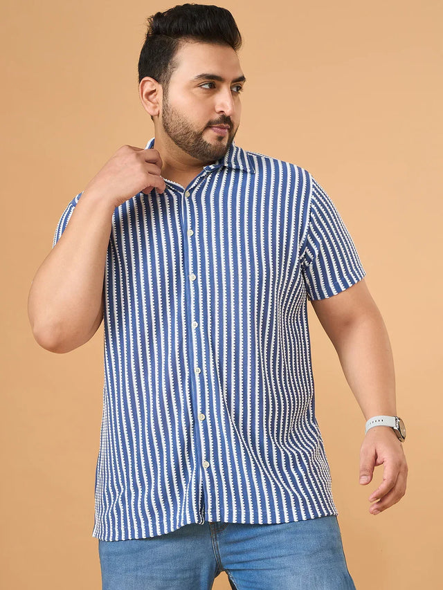 Plus size man in blue and white striped short sleeve shirt with jeans against beige background