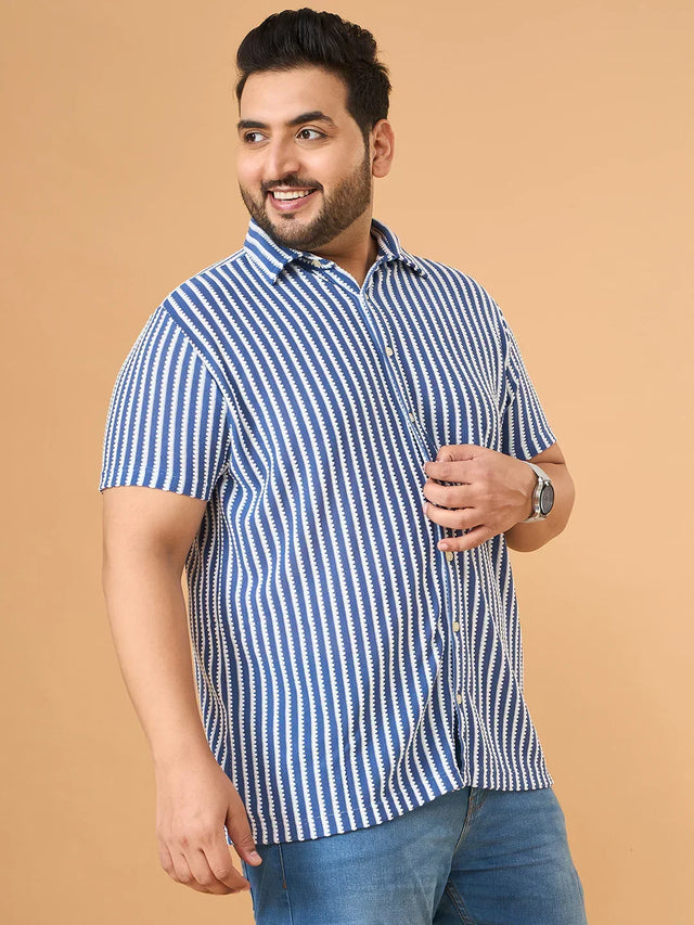 Plus size man in blue and white striped short sleeve shirt and jeans against beige background