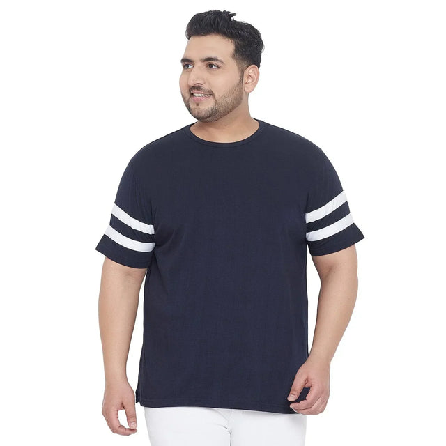 Plus size man in navy blue t-shirt with white double sleeve stripes, white pants, front view