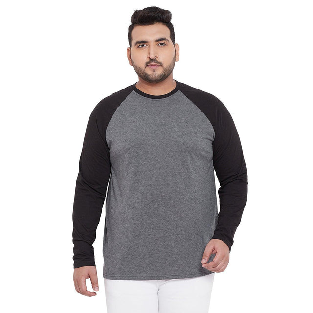 Plus size man wearing a grey and black raglan long sleeve t-shirt with white pants